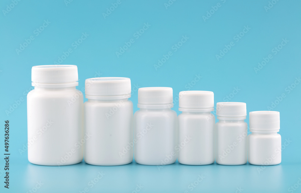 A row of decreasing white medicine bottles on a blue background A row of decreasing white medicine bottles on a blue background