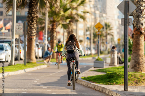 unknown woman riding a bicycle on bikeway at sunset in La Serena