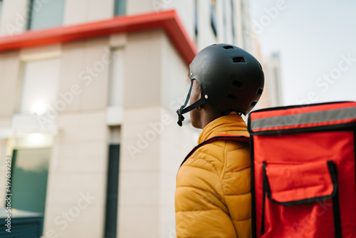 Black courier standing near house at delivery address photo