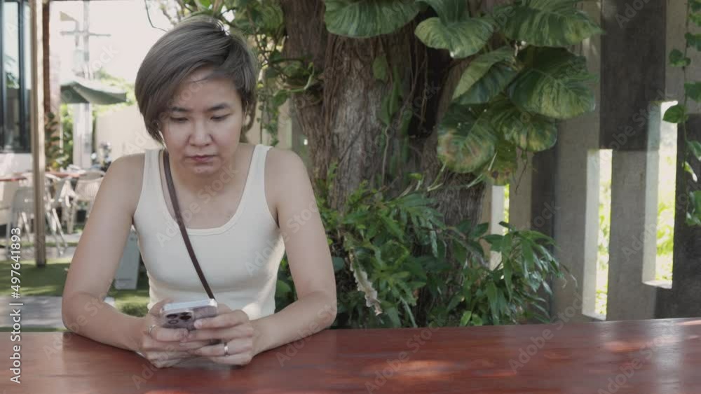 Beautiful and young asian woman is holding and using smartphone to connect to people in coffee shop with casual dress to show concept of modern lifestyle for doing work and business anywhere. Beautiful and young asian woman is holding and using smartphone to connect to people in coffee shop with casual dress to show concept of modern lifestyle for doing work and business anywhere.