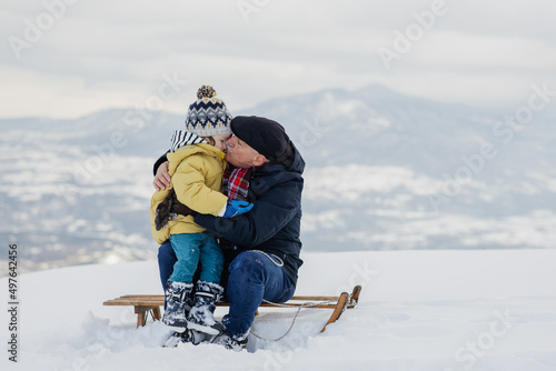 Grandpa And Grandson having fun on the snow photo