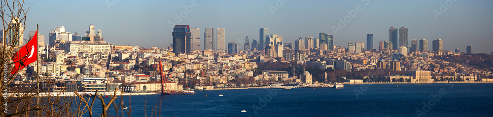 Picturesque view of modern cityscape of Istanbul from Topkapi across Golden Horn bay and Bosphorus with national Turkish flag waving on pole in foreground