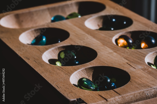 Selective focus on glass beads on a wooden mancala board photo