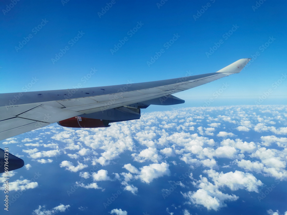 View from the porthole on the wing of an airplane with a red aircraft engine flying over beautiful white clouds and the sea. View from the porthole on the wing of an airplane with a red aircraft engine flying over beautiful white clouds and the sea.