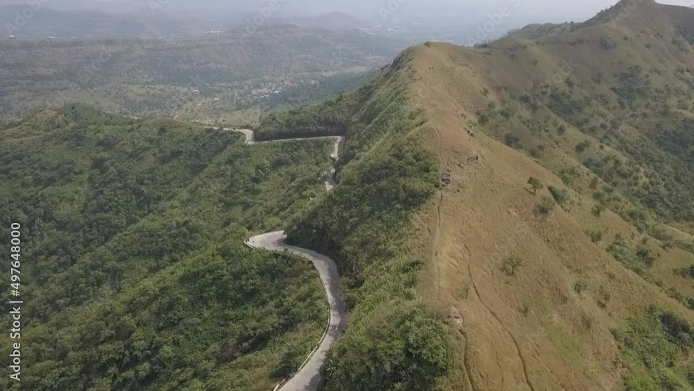 Rising aerial shows twisty road cut into side of steep mountain slope Rising aerial shows twisty road cut into side of steep mountain slope