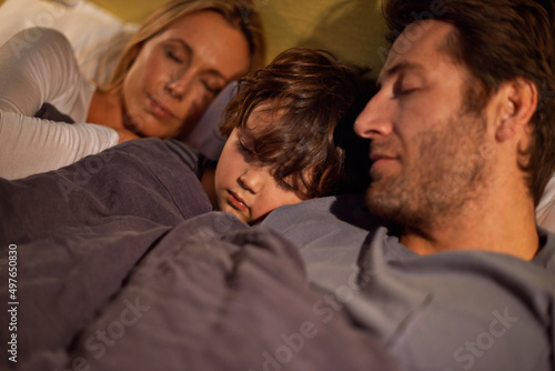 Off to dreamland together. Shot of a young family sleeping beside each other.