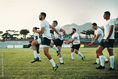 They take their training sessions very seriously. Full length shot of a group of young rugby players training with bands on the field during the day.