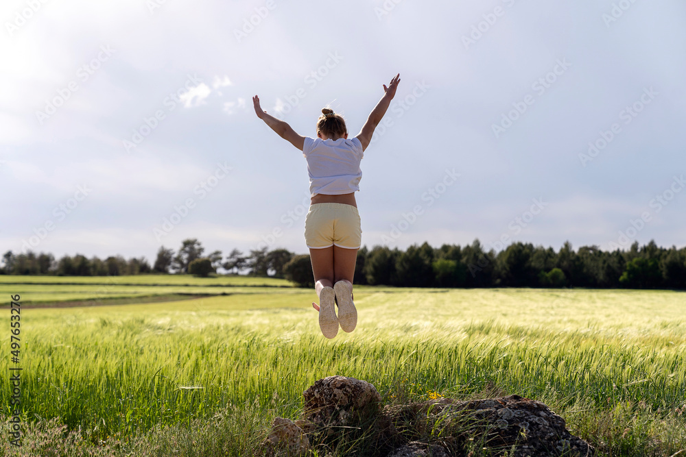 Anonymous woman jumping in field in countryside Anonymous woman jumping in field in countryside