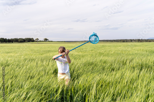 Carefree girl catching insects with net in field photo