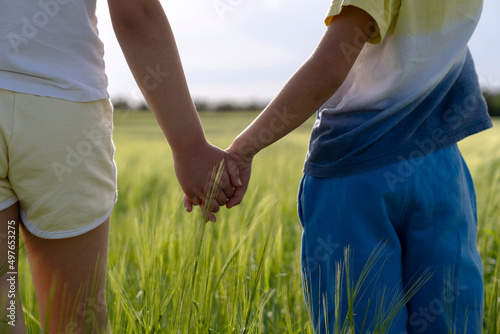 Kids holding hands in grassy field in countryside