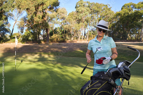 Lady golfer taking putte from gold bag photo