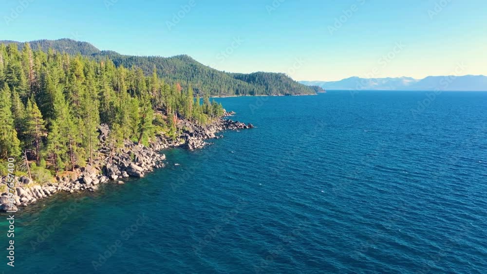 Aerial Drone Flying Over Clear Blue Waters of Lake George, New York With Rocky Shoreline And Thick Pine Tree Forest In Mountains Aerial Drone Flying Over Clear Blue Waters of Lake George, New York With Rocky Shoreline And Thick Pine Tree Forest In Mountains