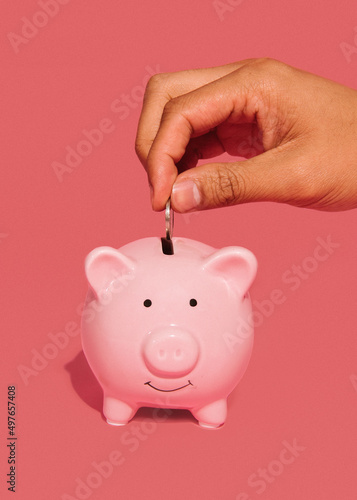 Hand dropping coin in piggy bank photo