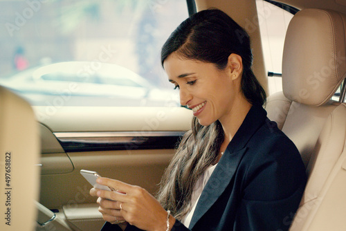 That one specific morning text can change your whole day. Shot of an attractive young businesswoman using her cellphone inside a car while traveling to work.