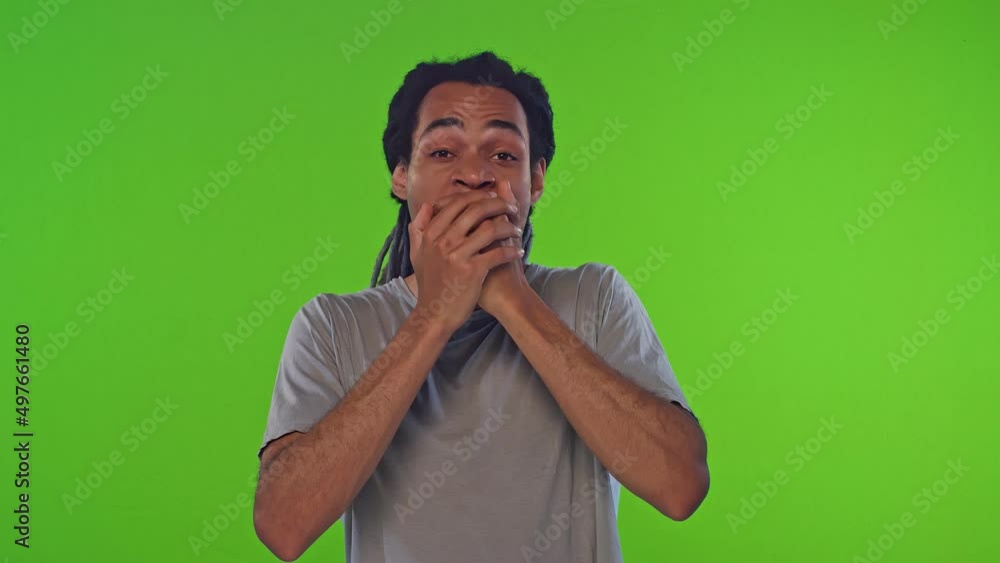 Young tired long haired African American man millennial yawns due to fatigue covers mouth with hand wants to sleep after hard day at university or college stands on chroma key studio background. Young tired long haired African American man millennial yawns due to fatigue covers mouth with hand wants to sleep after hard day at university or college stands on chroma key studio background.