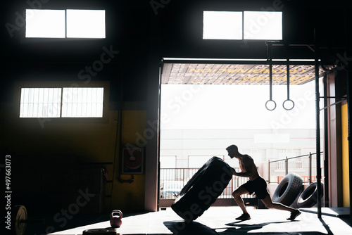 Determined man doing tire flip exercise during training photo