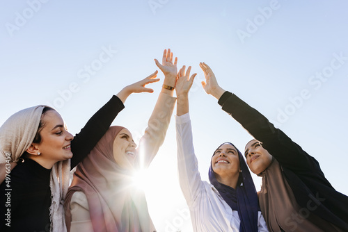 Cheerful Muslim women in hijab clasping hands in the air photo
