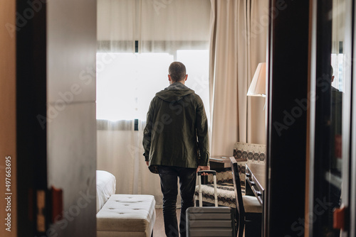 Man with suitcase entering hotel room during trip photo