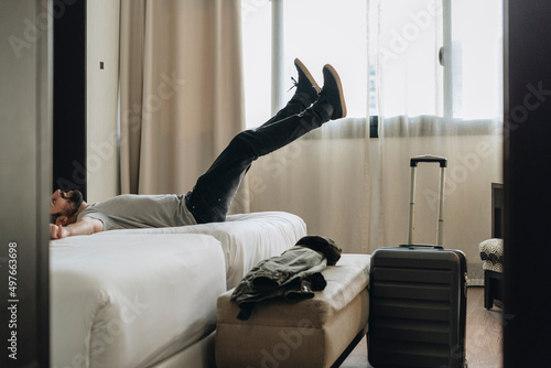 Man relaxing on bed in hotel room after flight