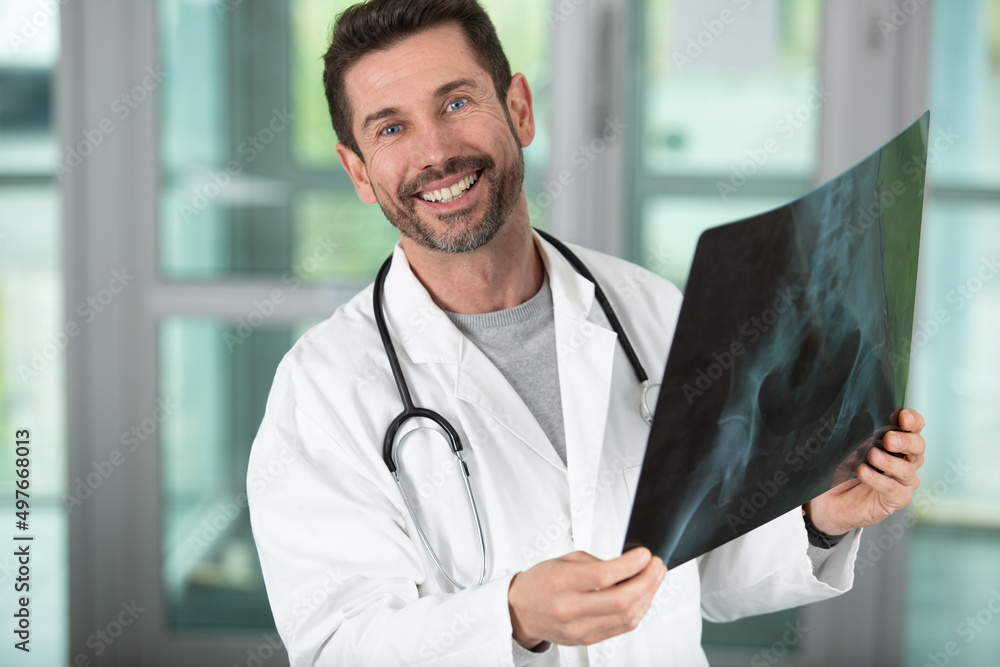 attractive doctor examining an x-ray and smiling at the camera attractive doctor examining an x-ray and smiling at the camera