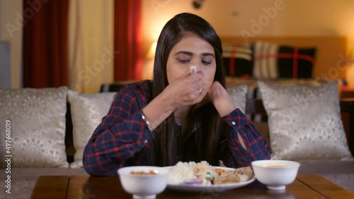 A young girl having a healthy homecooked meal while sitting alone - simple food  North Indian cuisine. A beautiful Indian lady having dinner while sitting in her living room - late-night  busy sche... photo