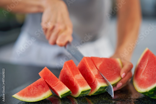 Nice adult woman with watermelon in the kitchen