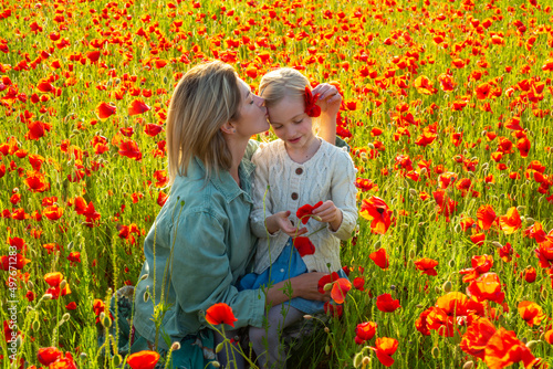 Mother with daughter outdoor in poppy field. Mom hugs lovely child on poppies background. Family in the field of spring blossom flowering meadow. Mother and daughter on spring. © Volodymyr