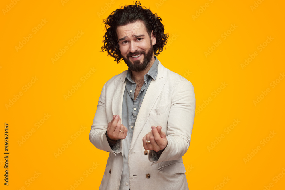 Smiling man making money gesture against yellow wall Smiling man making money gesture against yellow wall