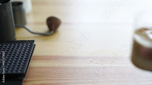 hand of barista grab small cup of chilled latte coffee on wood table
