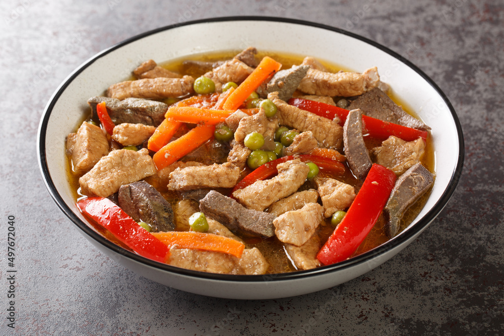 Igado is a popular dish from the Philippines made from pork tenderloin, pork liver, and vegetables closeup in the plate on the table. Horizontal Igado is a popular dish from the Philippines made from pork tenderloin, pork liver, and vegetables closeup in the plate on the table. Horizontal