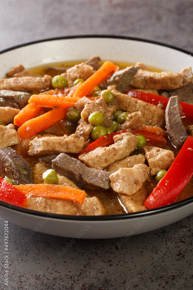 Igado is a Filipino spiced pork and liver dish closeup in the plate on the table. Vertical Igado is a Filipino spiced pork and liver dish closeup in the plate on the table. Vertical