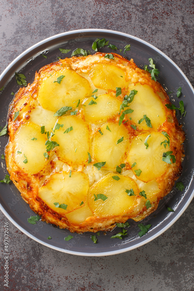 Pan haggerty is a traditional Northumbrian vegetarian side dish containing potatoes, onion and cheese closeup in the plate on the table. Vertical top view from above Pan haggerty is a traditional Northumbrian vegetarian side dish containing potatoes, onion and cheese closeup in the plate on the table. Vertical top view from above