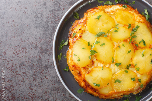 Pan Haggerty Potatoes feature sliced potatoes, sauteed Onions, topped with Dubliner Cheese closeup in the plate on the table. Horizontal top view from above photo