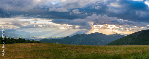 Sunset dramatic sky over Fabriano city, Marche, Italy. Sunbeams among clouds above unique hills and mountains landscape, emotional feeling concept.