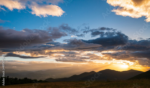 Sunset dramatic sky over Fabriano city, Marche, Italy. Sunbeams among clouds above unique hills and mountains landscape, emotional feeling concept.
