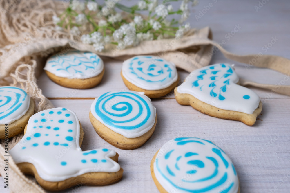 Gingerbread in the shape of eggs and rabbits on a white wooden table, eco bag and flowers, the concept of preparation for Easter Gingerbread in the shape of eggs and rabbits on a white wooden table, eco bag and flowers, the concept of preparation for Easter