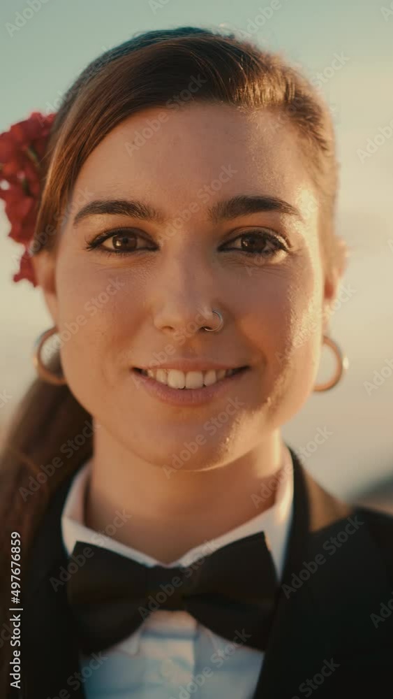 Vertical Screen: Portrait of a Happy Young Woman Wearing a Stylish Suit, Bow Tie, Nose Ring and Decorative Flower is Posing for Camera. Beautiful Multiethnic Caucasian Woman Smiling. Warm Color Edit. Vertical Screen: Portrait of a Happy Young Woman Wearing a Stylish Suit, Bow Tie, Nose Ring and Decorative Flower is Posing for Camera. Beautiful Multiethnic Caucasian Woman Smiling. Warm Color Edit.