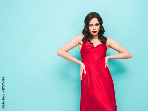 Beauty portrait of young brunette woman with evening makeup and perfect clean skin. Sexy model with curly hair posing in studio. With red bright natural lips.In red dress