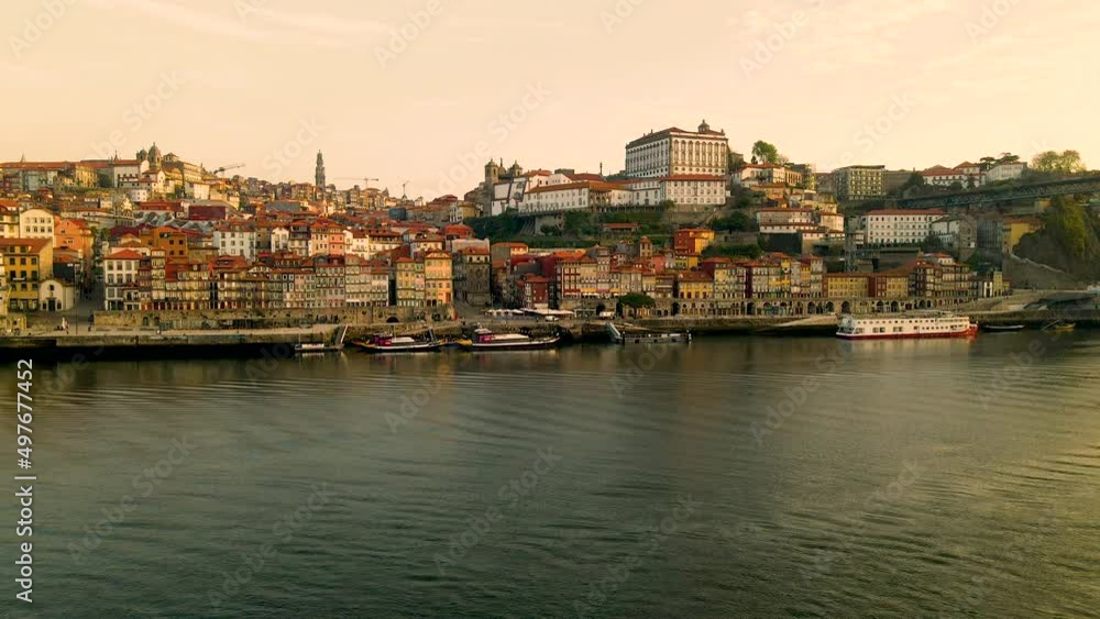 Descending shot of magnificent coastal city of Oporto during sunrise time with colorful houses and university on hilltop - Tranquil Douro River with docking boats at pier Descending shot of magnificent coastal city of Oporto during sunrise time with colorful houses and university on hilltop - Tranquil Douro River with docking boats at pier