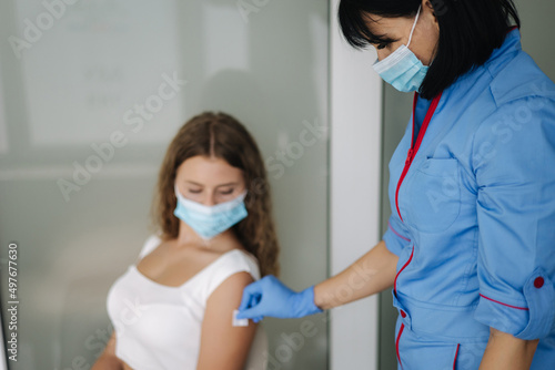 Woman in medical face mask getting Covid-19. Flu vaccine at the hospital. Professional nurse giving antiviral injection to female patient. Vaccination  disease prevention concept. Close-up of