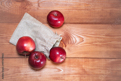 Top view on fresh red apples fell out of storage bags on a wooden background with a place for text: healthy snack, vitamins, healthy food, ingredients for baking recipes