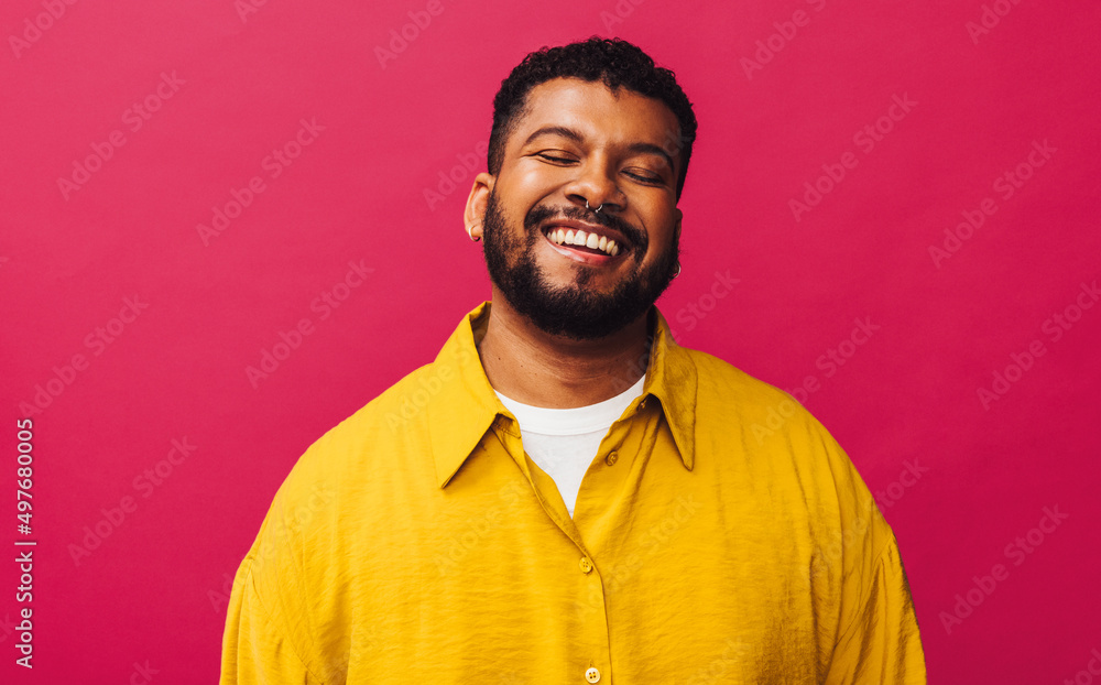 Obraz premium Happy young man smiling cheerfully with his eyes closed