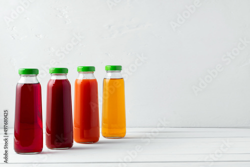 Glass bottles of different juices on white background