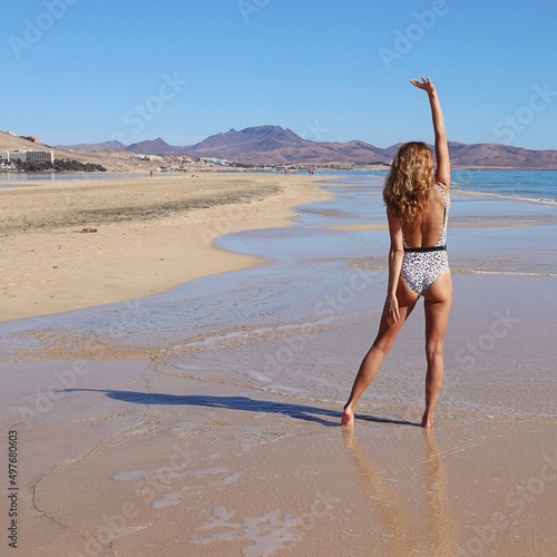 Radosna kobieta na plaży tyłem w stroju kąpielowym