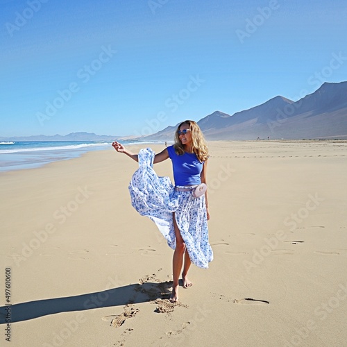 Radosna kobieta na plaży w długiej spódnicy