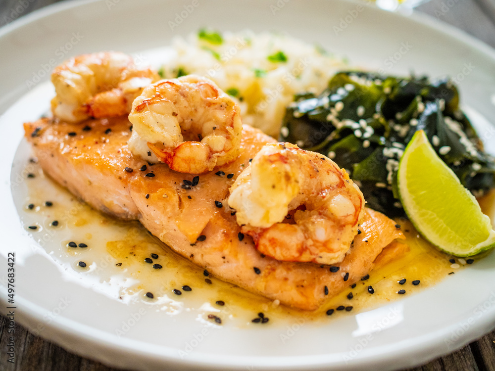 Fried salmon steak with prawns, white rice and spinach on wooden table
Fried salmon steak with prawns, white rice and spinach on wooden table