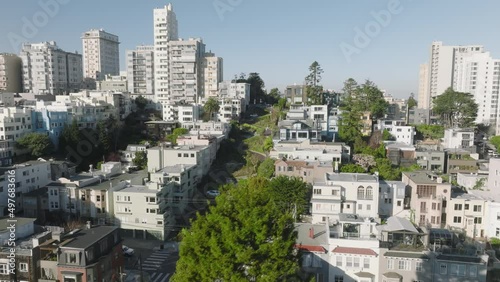 Scenic view of curving road along residential block with beautiful architecture. Aerial view of modern cityscape with lush greenery of Lombard street in San Francisco. High quality 4k footage