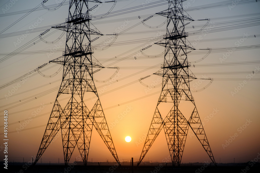 Electricity towers at sunset makes the sun between the towers is very beautiful.