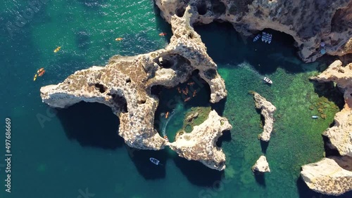 Aerial drone shot of kayaks and boats passing around magical Ponta da Piedade limestone cliffs. Exploring caves and tunnels of Lagos, Algarve, South of Portugal. Travel and adventure. Nomad life.
