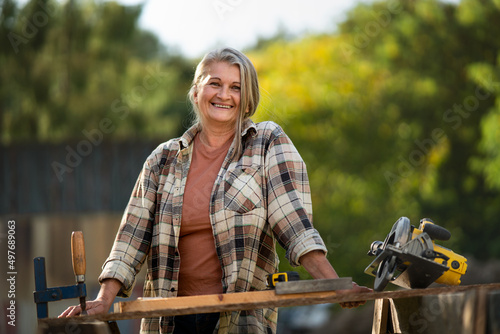 Tableau sur toile Happy handy female carpenter working in carpentry diy workshop outdoors with cir